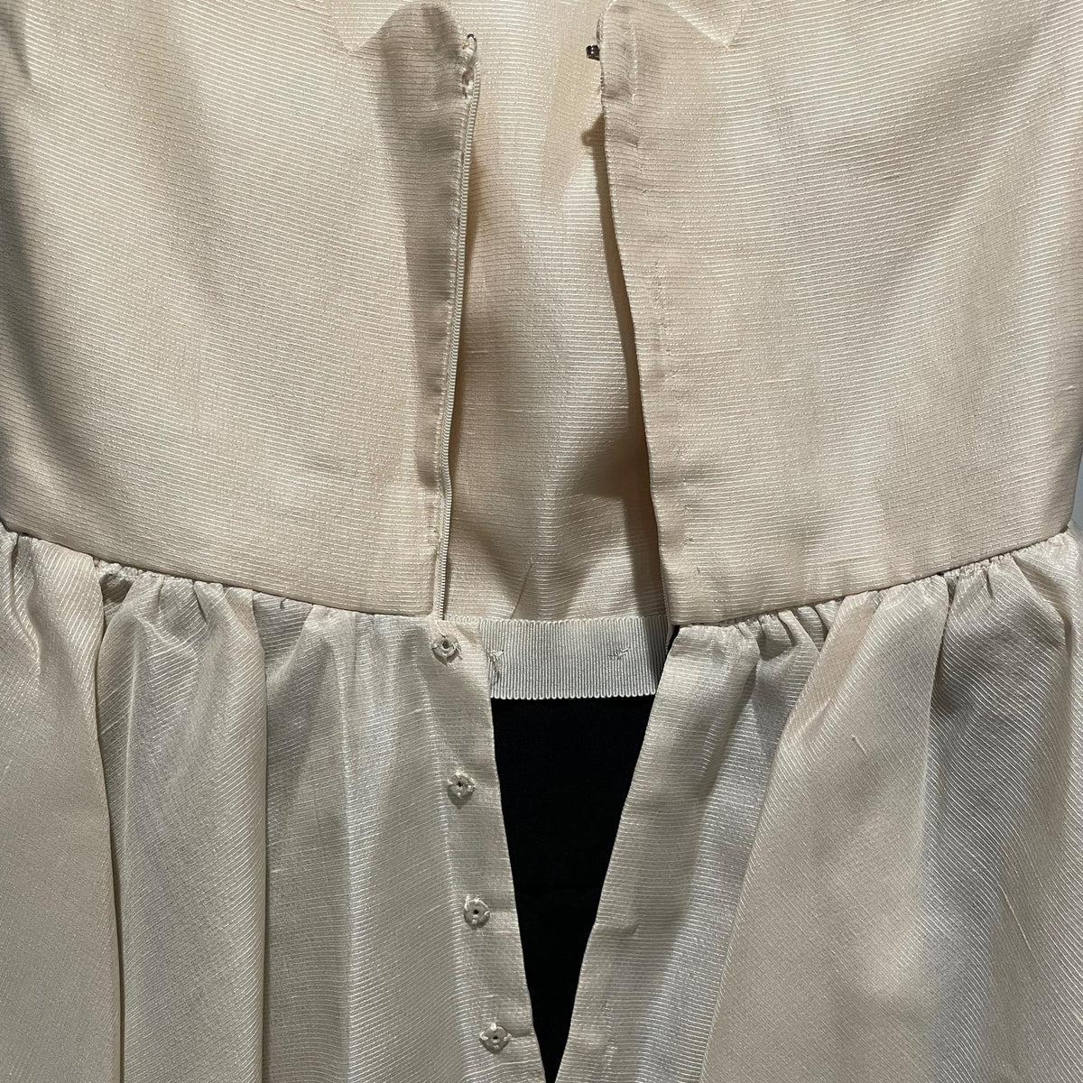 Interior detail of hook-and-eye and zipper at ivory bodice waist
